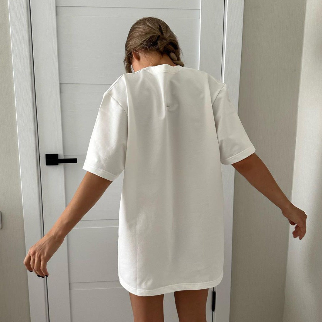 Frau in weißem T-Shirt, Rückenansicht, vor weißer Tür. Minimalistischer Stil, lässige Mode, Sommeroutfit, bequemes Baumwollshirt.