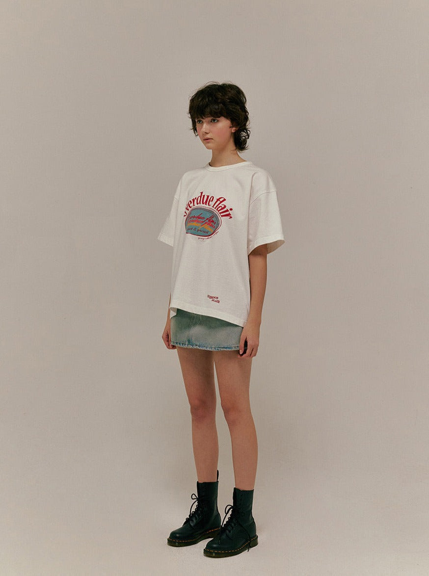 Frau in weißem T-Shirt mit rotem Aufdruck und Jeansshorts, trägt schwarze Stiefel. Modetrend, lässiger Stil, urbaner Look, Streetwear.