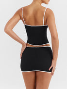 Schwarzes Minikleid mit weißen Akzenten, figurbetont, Spaghettiträger, elegantes Design, ideal für Partys und Abendveranstaltungen.