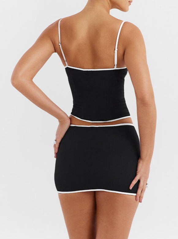 Schwarzes Minikleid mit weißen Akzenten, figurbetont, Spaghettiträger, elegantes Design, ideal für Partys und Abendveranstaltungen.