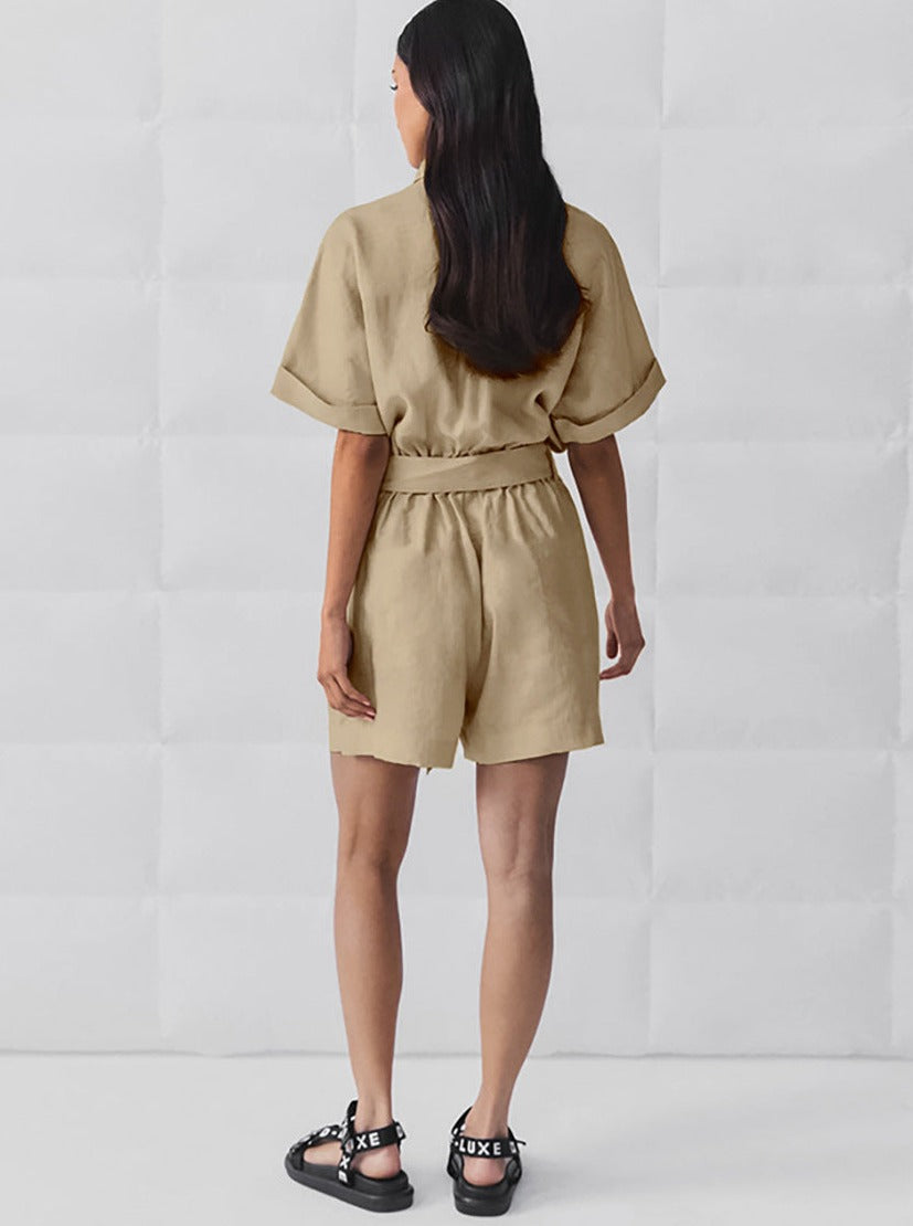 Frau in beigem Leinen-Overall, Rückansicht, mit schwarzen Sandalen. Modetrend, Sommeroutfit, lässiger Stil, Damenbekleidung, bequem.