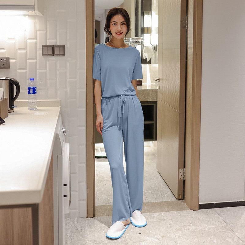 Frau in hellblauem Pyjama-Set im modernen Schlafzimmer. Bequeme Nachtwäsche, stilvoll und gemütlich, ideal für entspannte Abende zu Hause.