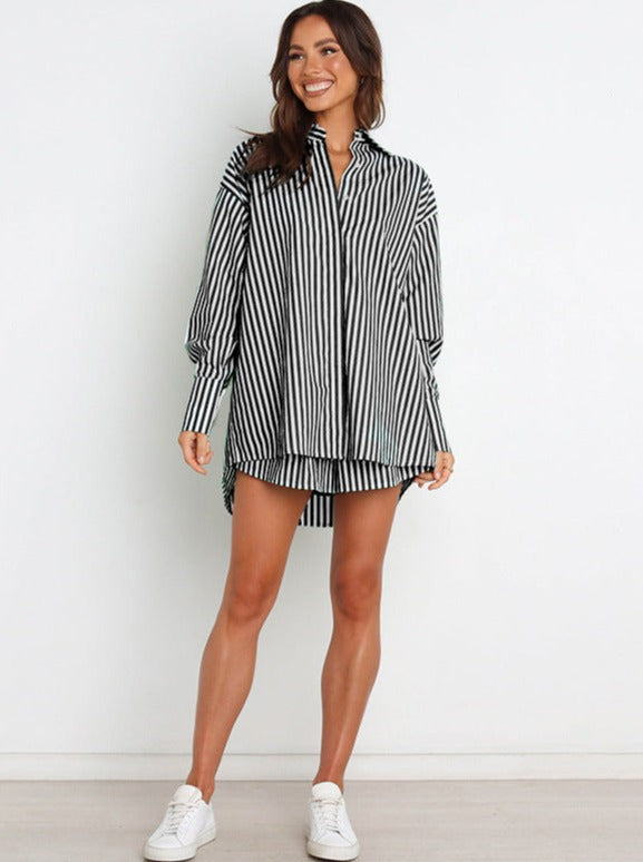 Frau trägt gestreiftes Hemdkleid, schwarz-weiß, lässig, langärmelig, modern. Perfekt für Freizeitmode, kombiniert mit weißen Sneakers.