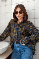 Frau mit braunem Haar trägt kariertes Hemd, blaue Jeans und Sonnenbrille. Modetrend, lässiger Stil, urbane Mode, Damenbekleidung.
