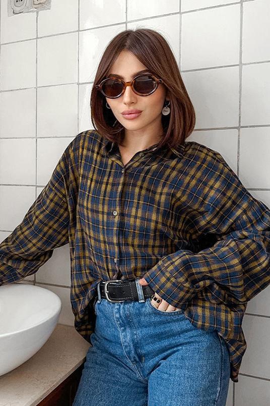 Frau mit braunem Haar trägt kariertes Hemd, blaue Jeans und Sonnenbrille. Modetrend, lässiger Stil, urbane Mode, Damenbekleidung.