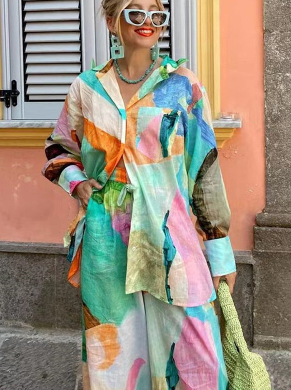 Frau in bunter, abstrakter Bluse und Rock, trägt weiße Sonnenbrille und grünen Strickbeutel. Modetrend, Sommeroutfit, farbenfrohe Kleidung.
