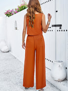 Frau in orangefarbenem Jumpsuit, Sommermode, ärmelloses Design, entspannter Stil, ideal für Strandurlaub, modische Damenbekleidung.