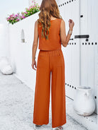 Frau in orangefarbenem Jumpsuit, Sommermode, lässiger Stil, ärmelloses Top, weite Hose, modisches Outfit, trendige Damenbekleidung.