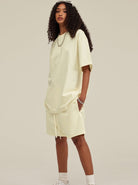 Frau in cremefarbenem Oversize-T-Shirt und Shorts, modisch, lässig, Streetwear, lockige Haare, minimalistisch, Sommeroutfit, urbaner Stil.