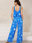 Frau in blauem, ärmellosem Sommeranzug mit maritimen Mustern, ideal für Strandmode. Perfekt für stilvolle, lässige Sommeroutfits.