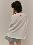 Person in weißem Oversize-T-Shirt und Jeansrock, Rückenansicht. Modetrend, lässiger Stil, minimalistisch, urban, Streetwear, Damenmode.