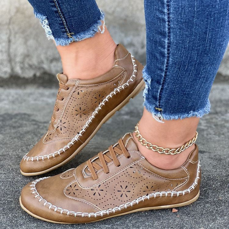 Damen-Ledersneaker in Braun mit Blumenmuster, handgenäht, kombiniert mit modischen Jeans. Bequeme Freizeitschuhe für den Alltag.