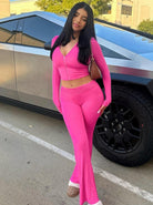 Frau in pinkem Trainingsanzug posiert vor einem futuristischen Auto. Modetrend, Streetstyle, sportliche Kleidung, urbaner Look, stilvoll.