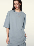 Graues Oversize-T-Shirt für Damen, lässiger Look, weicher Stoff, ideal für Streetwear und Freizeitmode, kombiniert mit modischem Schmuck.