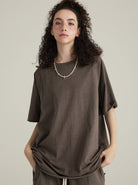 Frau in braunem T-Shirt, lässiger Stil, lockiges Haar, modisches Outfit, minimalistisch, entspannter Look, trendige Damenmode, urbaner Chic.