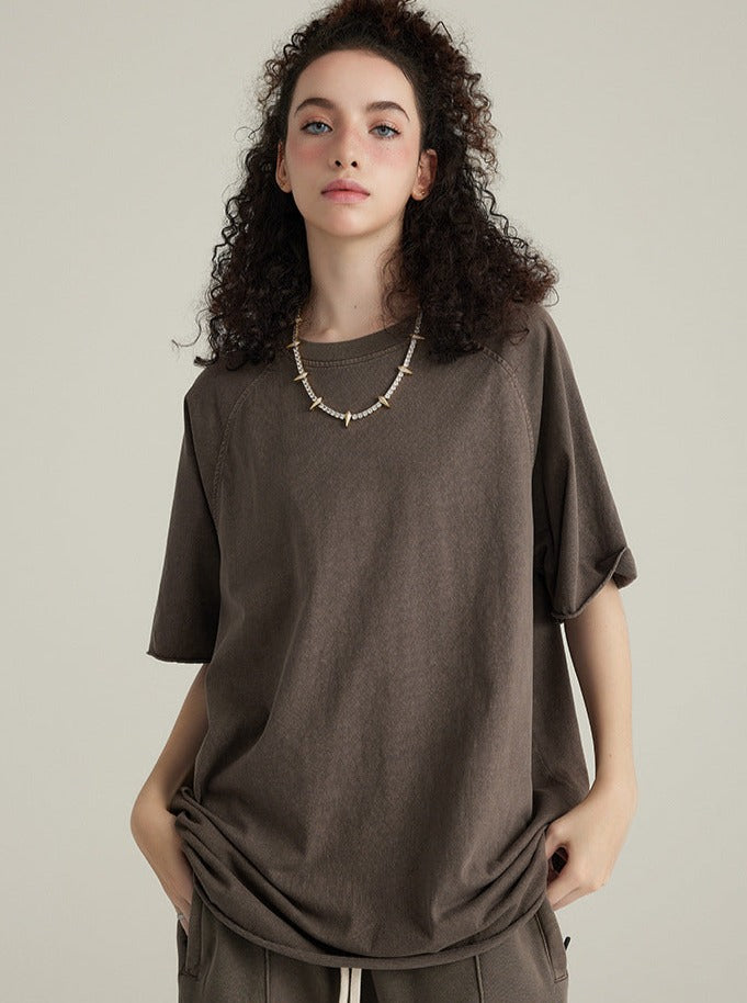 Frau in braunem T-Shirt, lässiger Stil, lockiges Haar, modisches Outfit, minimalistisch, entspannter Look, trendige Damenmode, urbaner Chic.