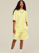 Gelbes Oversize-T-Shirt und Shorts-Set für Damen, lässiger Look, ideal für Sommermode. Perfekt kombiniert mit Sneakers und Kette.