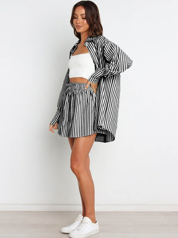 Frau in gestreiftem Zweiteiler: Schwarz-Weiß-Hemd und Shorts, kombiniert mit weißem Top und Sneakers. Modetrend, lässiger Sommerlook.
