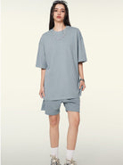 Frau in grauem Oversize-T-Shirt und Shorts, modisch, lässig, Streetwear, Sommeroutfit, trendige Kleidung, urbaner Stil, bequeme Passform.