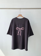 Schwarzes T-Shirt mit rosa Schleife und "La Vie en Rose"-Aufdruck. Modisches Design, lässiger Stil, hochwertiger Baumwollstoff.