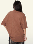 Braunes Oversize-T-Shirt, lässig geschnitten, aus Baumwolle, ideal für Streetwear. Kombiniert mit zerrissenen Jeans für einen urbanen Look.
