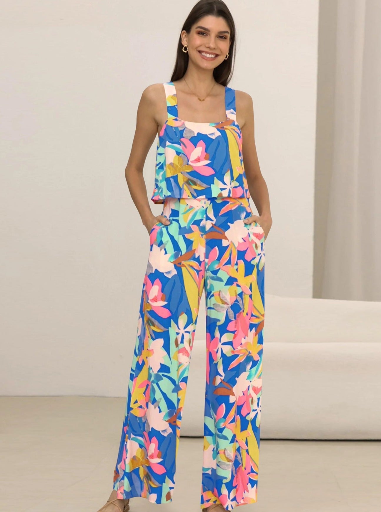 Frau in bunter, floraler Sommerhose und Top, lächelt. Modetrend 2023, Damenbekleidung, farbenfrohes Outfit, lässiger Stil, Sommermode.