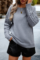 Grauer Strickpullover mit Zopfmuster, Damenmode, lässiger Herbstlook, weiches Material, stilvoller Langarm, ideal für kühle Tage.