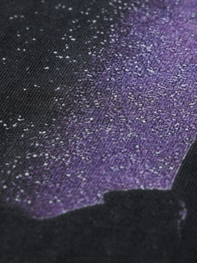 Nahaufnahme eines schwarzen Stoffes mit lila Sprenkelmuster. Ideal für Mode, Textildesign und kreative Bekleidung. Hochwertiger Stoff, trendiges Design.