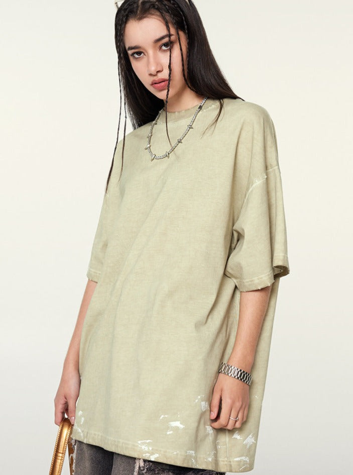 Frau in oversized T-Shirt, beige, mit Kettenhalskette. Modetrend, lässiger Stil, Streetwear, Damenmode, urbaner Look, Sommeroutfit.