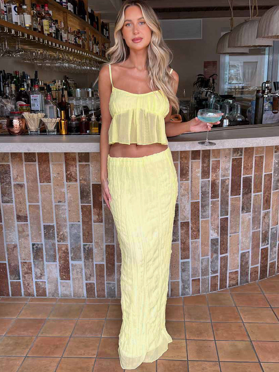 Frau in gelbem Sommerkleid an einer Bar, hält ein Cocktailglas. Perfekt für Strandmode, Sommeroutfits, elegante Freizeitkleidung.