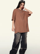 Frau in braunem Oversize-T-Shirt und schwarzen Cargo-Jeans mit Ketten, modisch und lässig, Streetwear, trendige Damenmode, urbaner Stil.