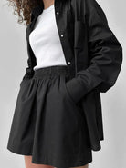 Schwarzes Hemd und Rock-Set für Damen, kombiniert mit weißem Top. Modisches Outfit, ideal für Freizeit und Büro. Eleganter, zeitloser Look.
