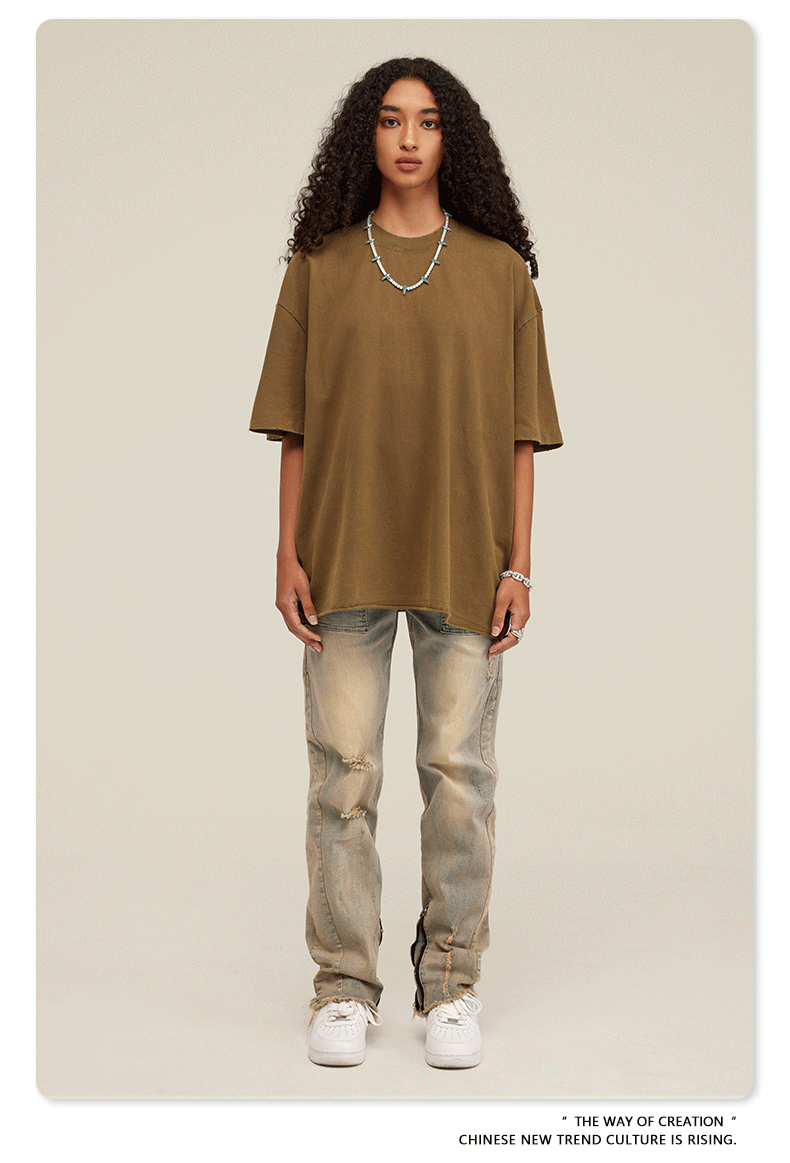 Frau in lässigem Outfit: braunes Oversize-T-Shirt, zerrissene Jeans, weiße Sneaker. Modetrend, Streetwear, urbaner Stil, Freizeitlook.