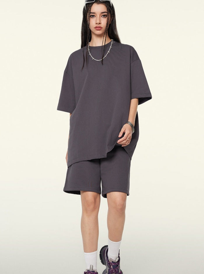 Frau in oversized grauem T-Shirt und Shorts, modischer Streetwear-Look, lässiger Stil, trendige Kleidung, urbaner Mode, Sneakers.
