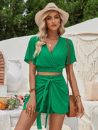 Frau in grünem Sommerkleid mit Strohhut, posiert stilvoll im Freien. Perfekt für Sommermode, Strandoutfits und Urlaubslooks.