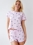 Damen-Pyjama-Set in Rosa mit schwarzen Herzmustern, bestehend aus T-Shirt und Shorts. Bequem, modisch, ideal für erholsamen Schlaf.