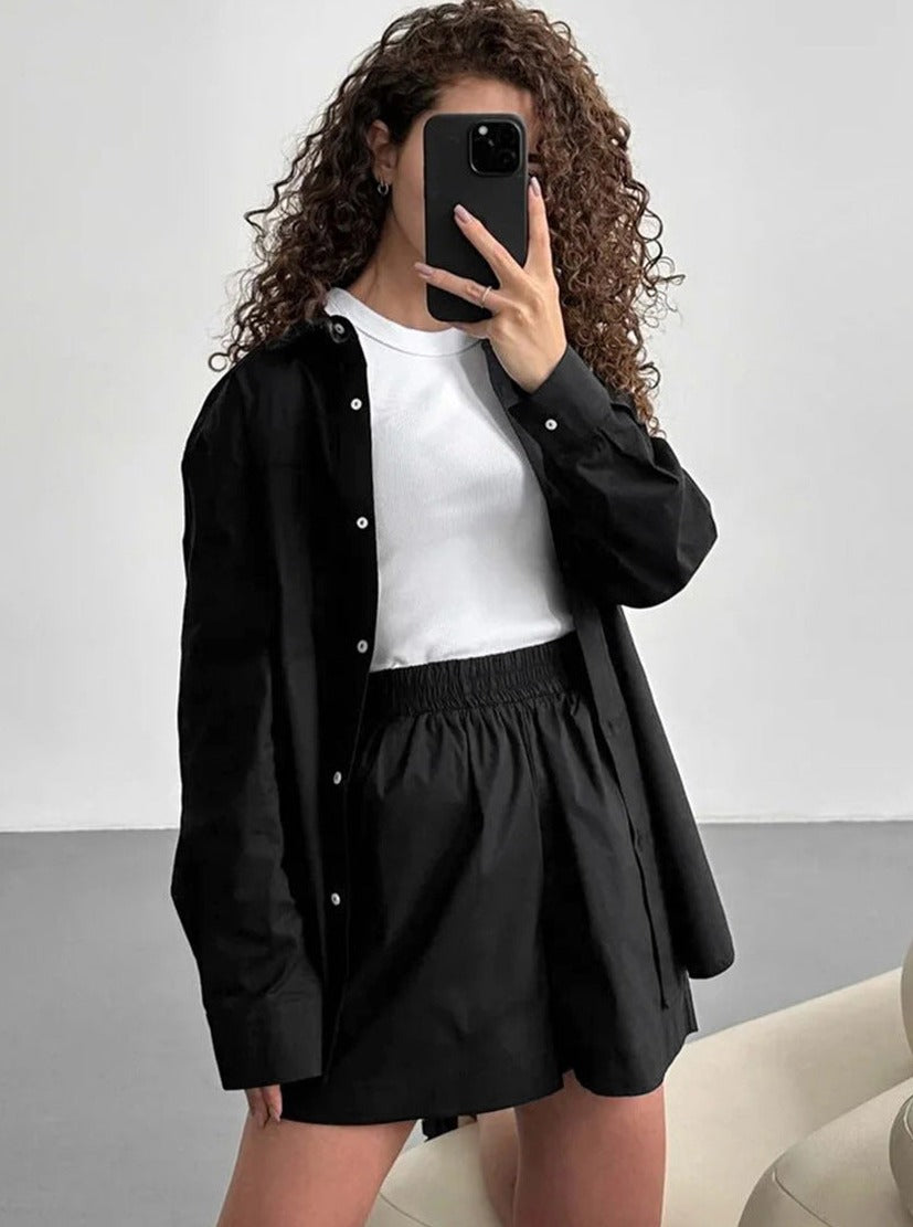 Frau in schwarzem Hemd und Rock, weißem T-Shirt, macht Selfie. Modetrend, lässiger Look, lockige Haare, stilvolle Damenbekleidung.