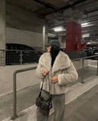 Frau in grauem Kunstpelzmantel und schwarzer Mütze in Tiefgarage. Modetrend, Wintermode, stilvolle Damenbekleidung, urbane Eleganz.