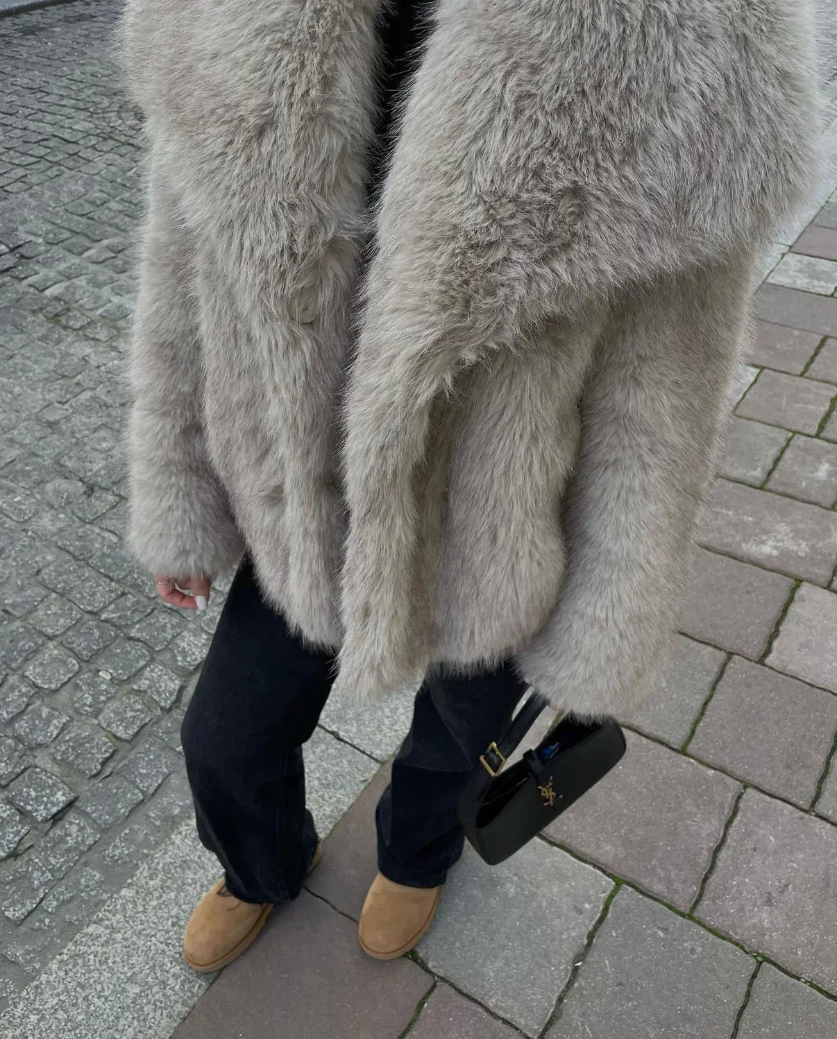 Damenmode: Eleganter, grauer Kunstpelzmantel kombiniert mit schwarzer Handtasche und braunen Stiefeln. Winteroutfit, stilvoll, warm.