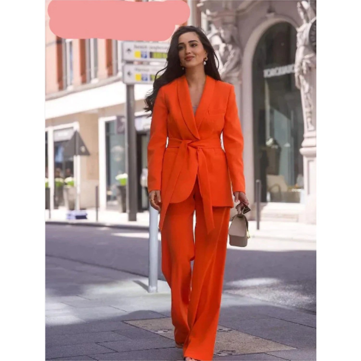 Frau in leuchtend orangefarbenem Anzug auf Stadtstraße, modisch und elegant. Keywords: Damenmode, Anzug, Streetstyle, Trend, Fashion.