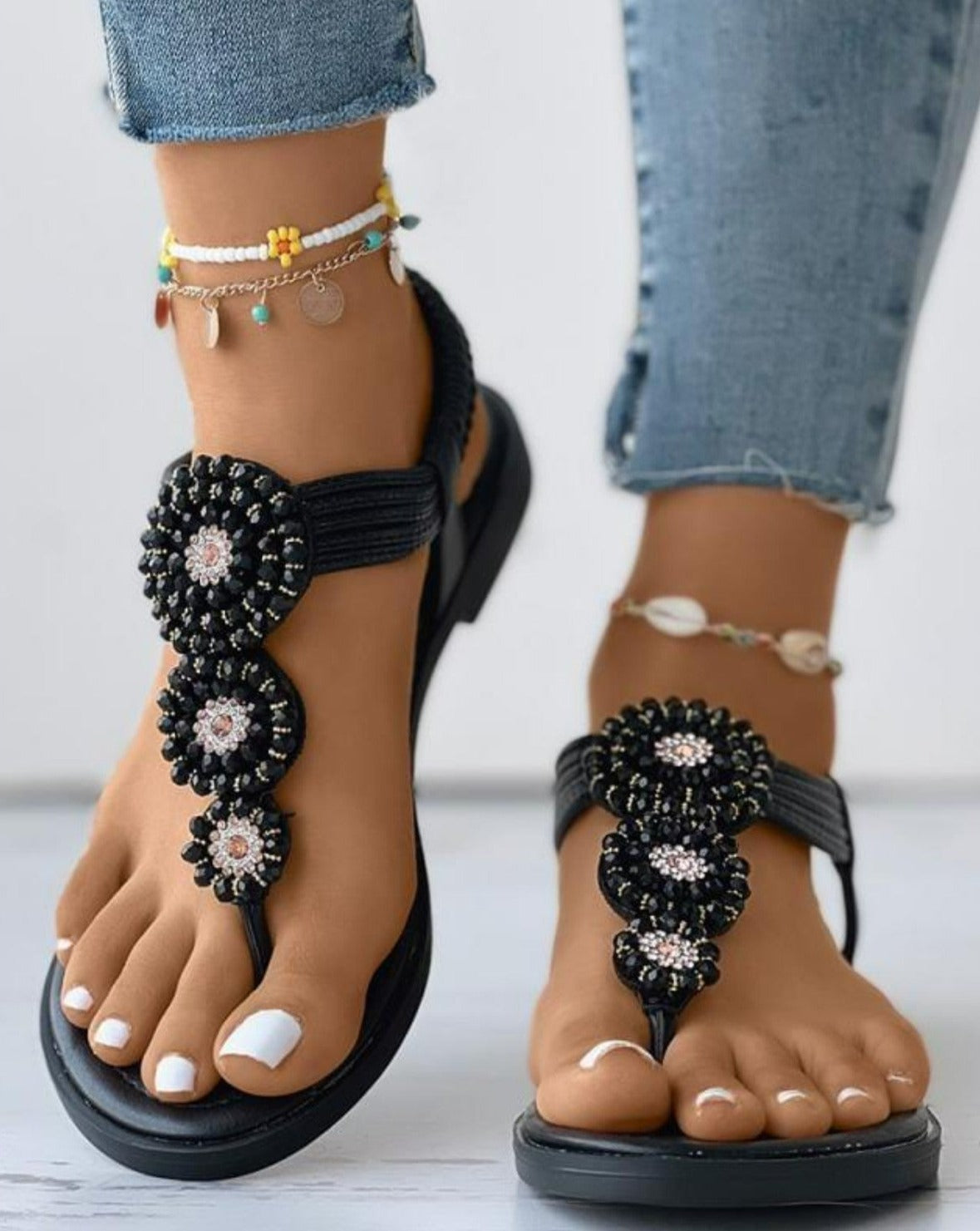 Schwarze Sandalen mit Perlenverzierung, ideal für Sommermode. Perfekt kombiniert mit Jeans und Fußkettchen. Bequeme und stilvolle Damen-Sandalen.