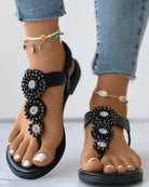 Schwarze Sandalen mit Perlenverzierung, ideal für Sommermode. Perfekt kombiniert mit Jeans und Fußkettchen. Bequeme und stilvolle Damen-Sandalen.