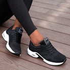 Schwarze Damen-Sneaker mit weißer Sohle, atmungsaktivem Mesh-Obermaterial, ideal für Sport und Freizeit. Trendige, bequeme Sportschuhe.