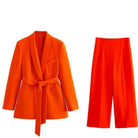 Eleganter orangefarbener Damenanzug mit Gürtel, bestehend aus Blazer und Hose. Perfekt für Business-Mode und stilvolle Auftritte.