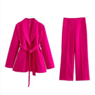 Eleganter pinker Hosenanzug für Damen, bestehend aus Blazer mit Gürtel und weiten Hosen. Perfekt für Business und besondere Anlässe.