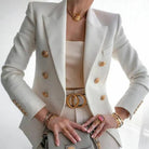 Eleganter cremefarbener Blazer mit goldenen Knöpfen, kombiniert mit passendem Gürtel und Schmuck. Perfekt für stilvolle Business-Mode.