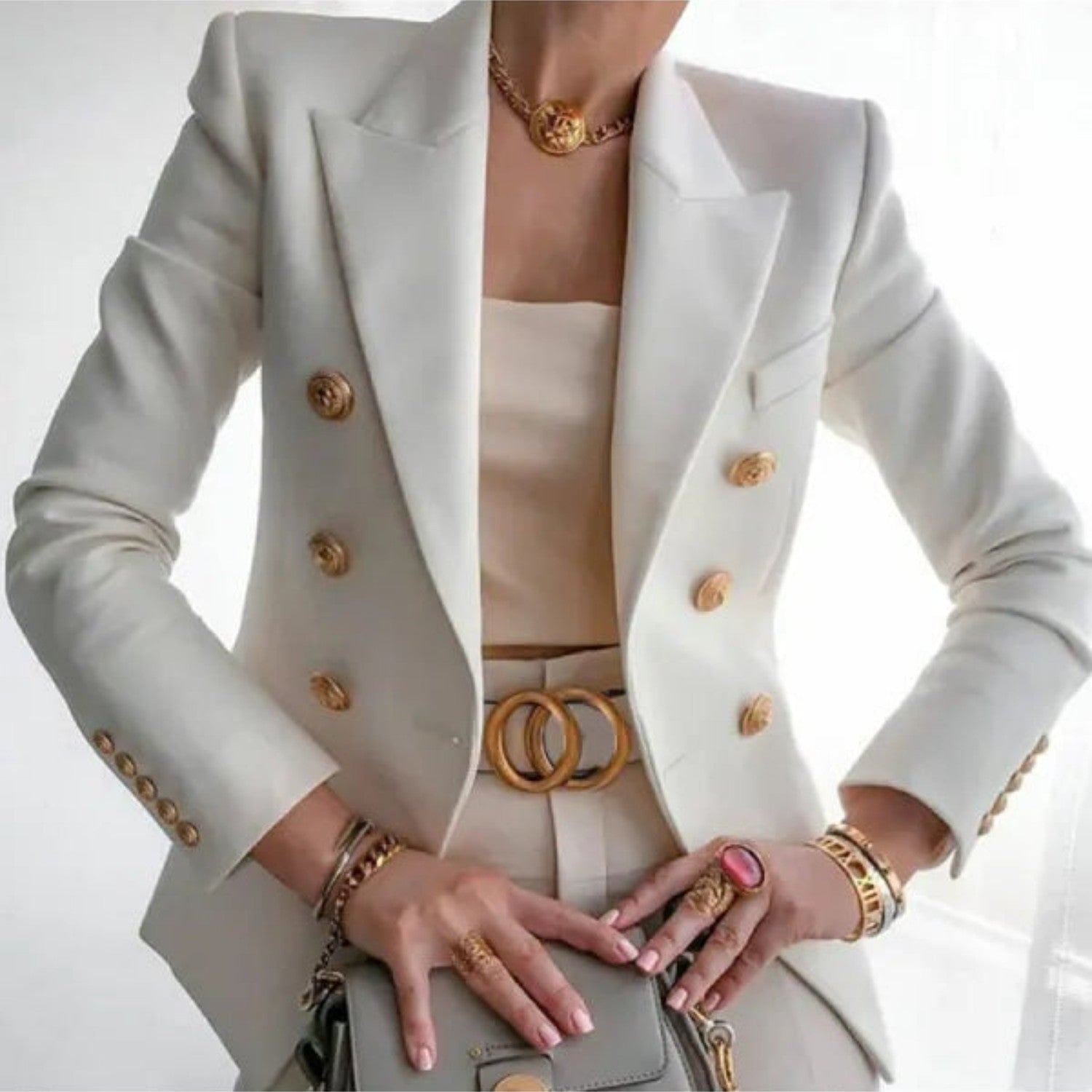 Eleganter cremefarbener Blazer mit goldenen Knöpfen, kombiniert mit passendem Gürtel und Schmuck. Perfekt für stilvolle Business-Mode.