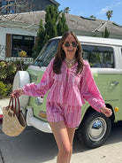 Frau in rosa gestreiftem Shorts-Anzug vor grünem VW-Bus, Sommermode, Freizeitlook.