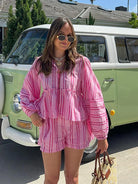 Frau in rosa gestreiftem Shorts-Anzug vor grünem VW-Bus, Sommermode, lässiger Stil.