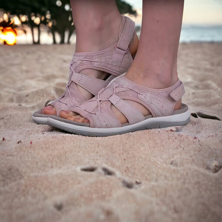 Bequeme Damen-Sandalen in Rosa auf Sandstrand, ideal für Sommer und Strandurlaub. Perfekte Passform, atmungsaktiv und stilvoll.